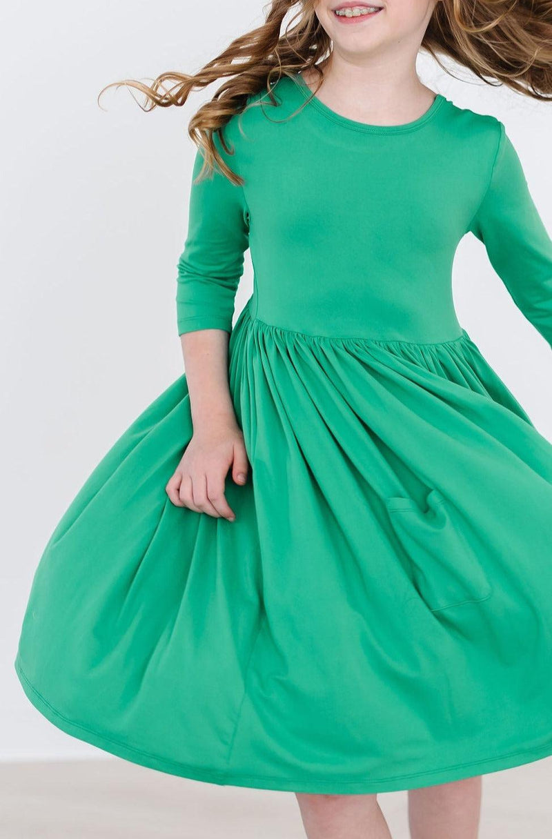 Kelly Green 3/4 Sleeve Pocket Twirl Dress in action, showcasing a young girl twirling joyfully in the vibrant green dress, perfect for play and celebration.