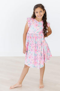 Girl wearing a pink floral flutter sleeve twirl dress with comfortable ruffle details for play.