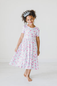 Girl wearing a pastel mermaid-scale twirl dress with short sleeves and a full skirt