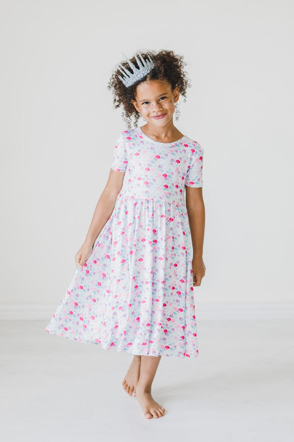 Girl wearing a pastel mermaid-scale twirl dress with short sleeves and a full skirt