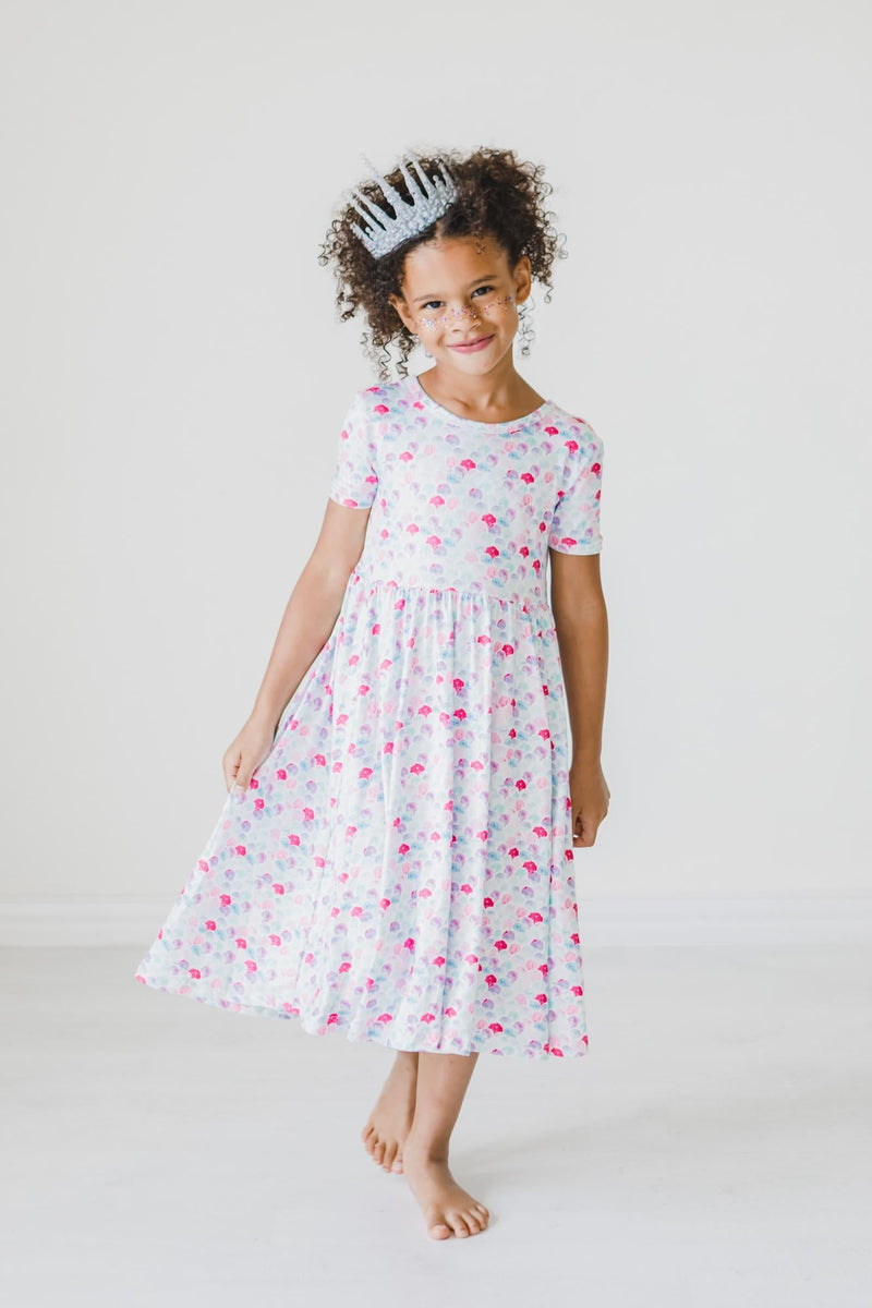 Girl wearing a pastel mermaid-scale twirl dress with short sleeves and a full skirt