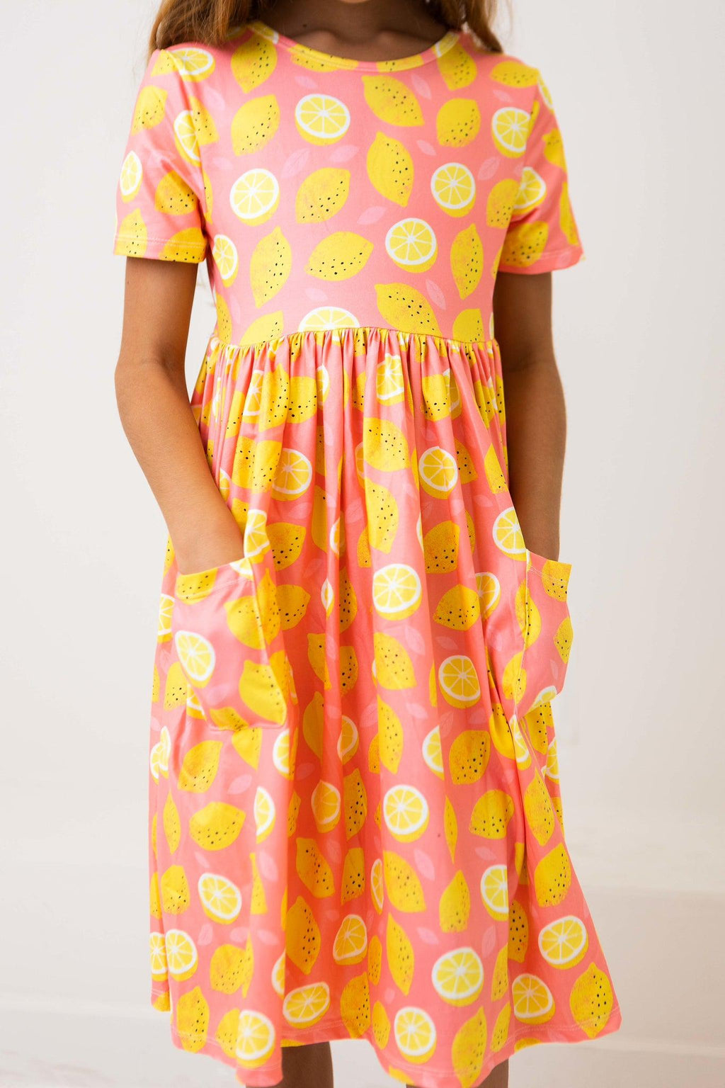 Lemon Squeezy S/S Pocket Twirl Dress by Mila & Rose, designed for playful kids, featuring a bright pink color with lemon patterns and convenient pockets.