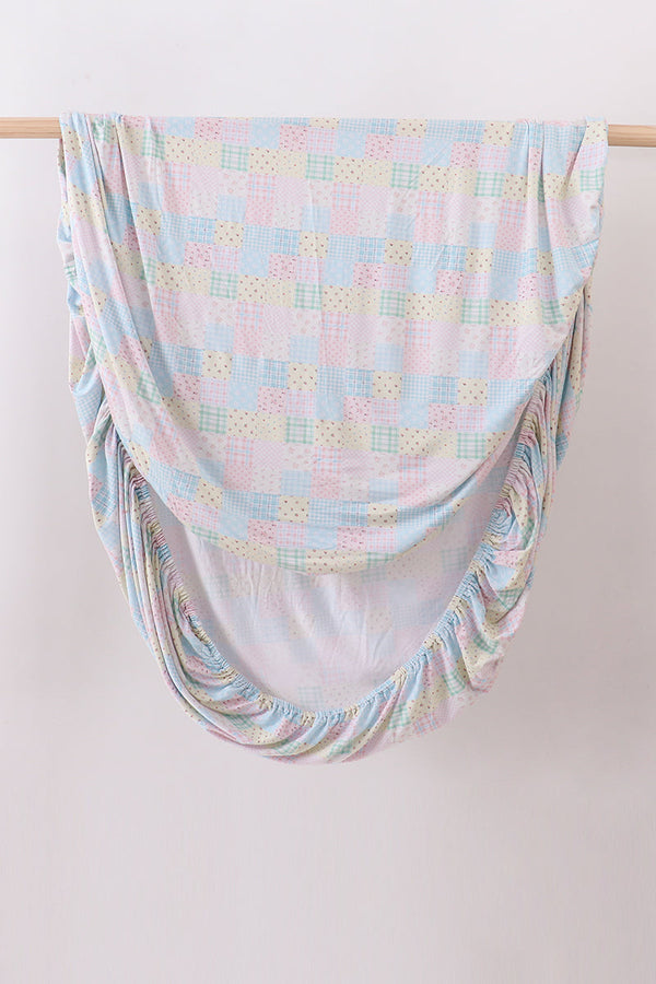 Pink floral checkered bamboo crib sheet with pastel patchwork pattern and elastic corners for soft, breathable baby bedding.