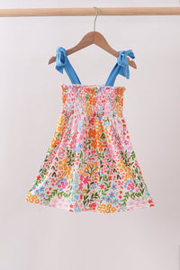 Colorful floral dress with blue straps on a hanger against a plain background