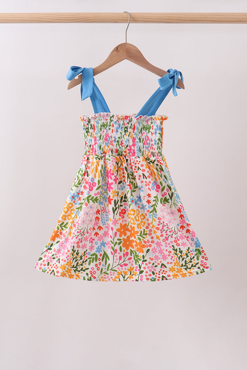 Floral dress with blue straps on a hanger against a white background