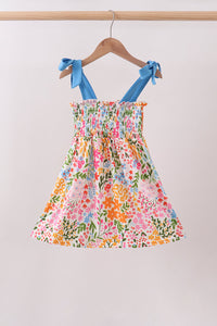 Floral dress with blue straps on a hanger against a white background