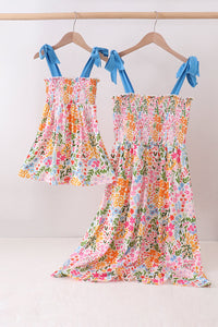 Floral dress with blue ribbon straps hanging on a rack against a white background