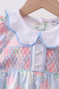 Children's dress with smocked details on a hanger, brand 'abby & otto' visible.