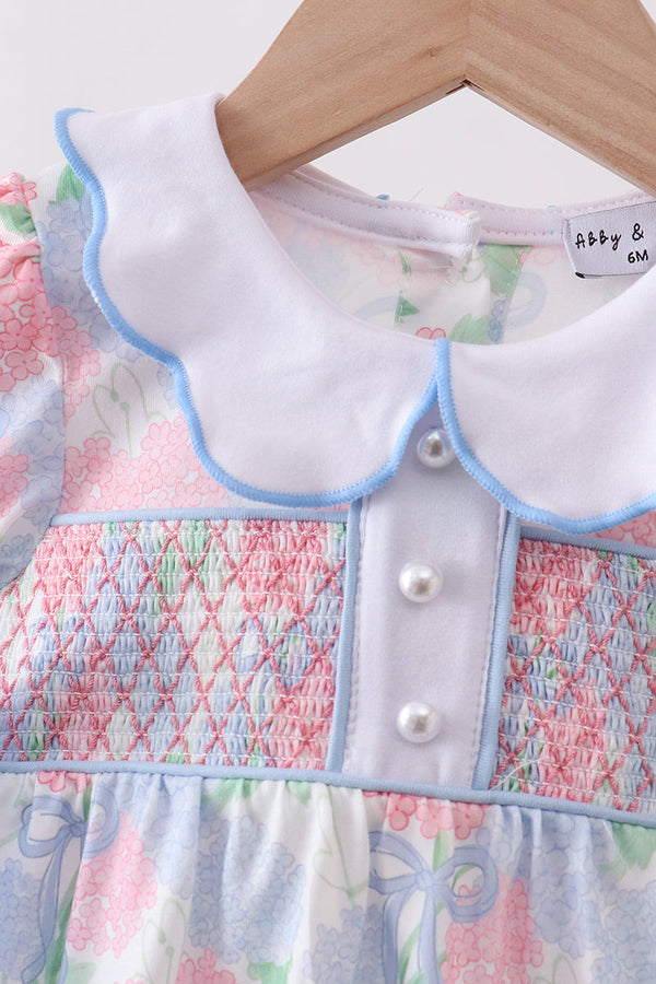 Children's dress with smocked details on a hanger, brand 'abby & otto' visible.