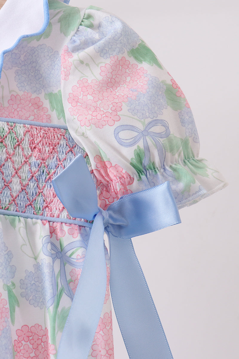 Floral-patterned baby outfit with a large blue bow on a light background