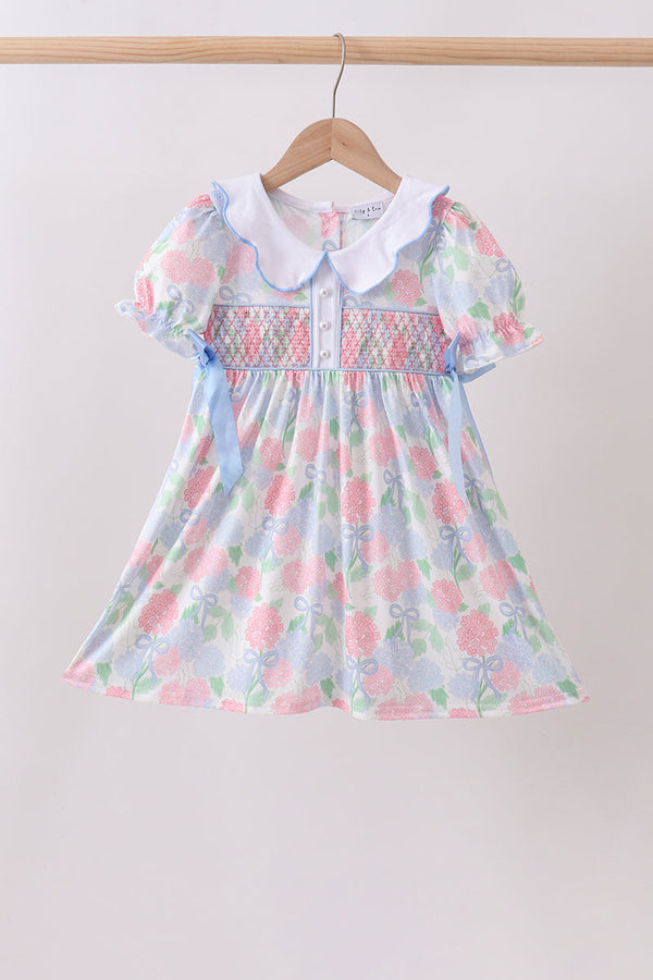 Blue hydrangea smocked pearl dress with pastel floral print, white collar, puff sleeves and ribbon accents.