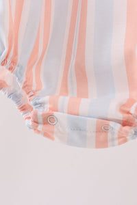 Close-up of pink and blue striped bubble fabric with gathered elastic hem and silver snap buttons for adjustable fit.