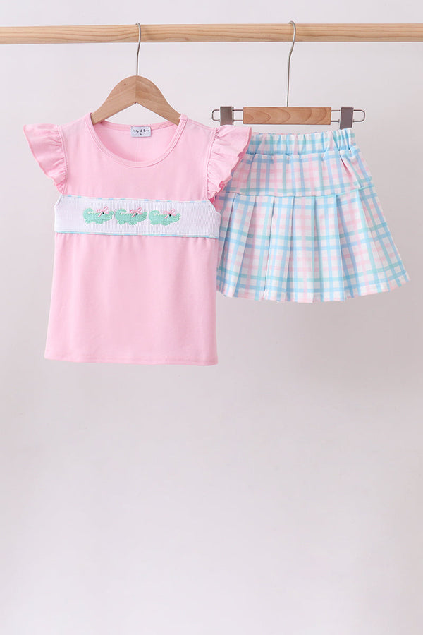 Two-piece pink crocodile-smocked top with ruffled sleeves and pastel blue-pink plaid skort.