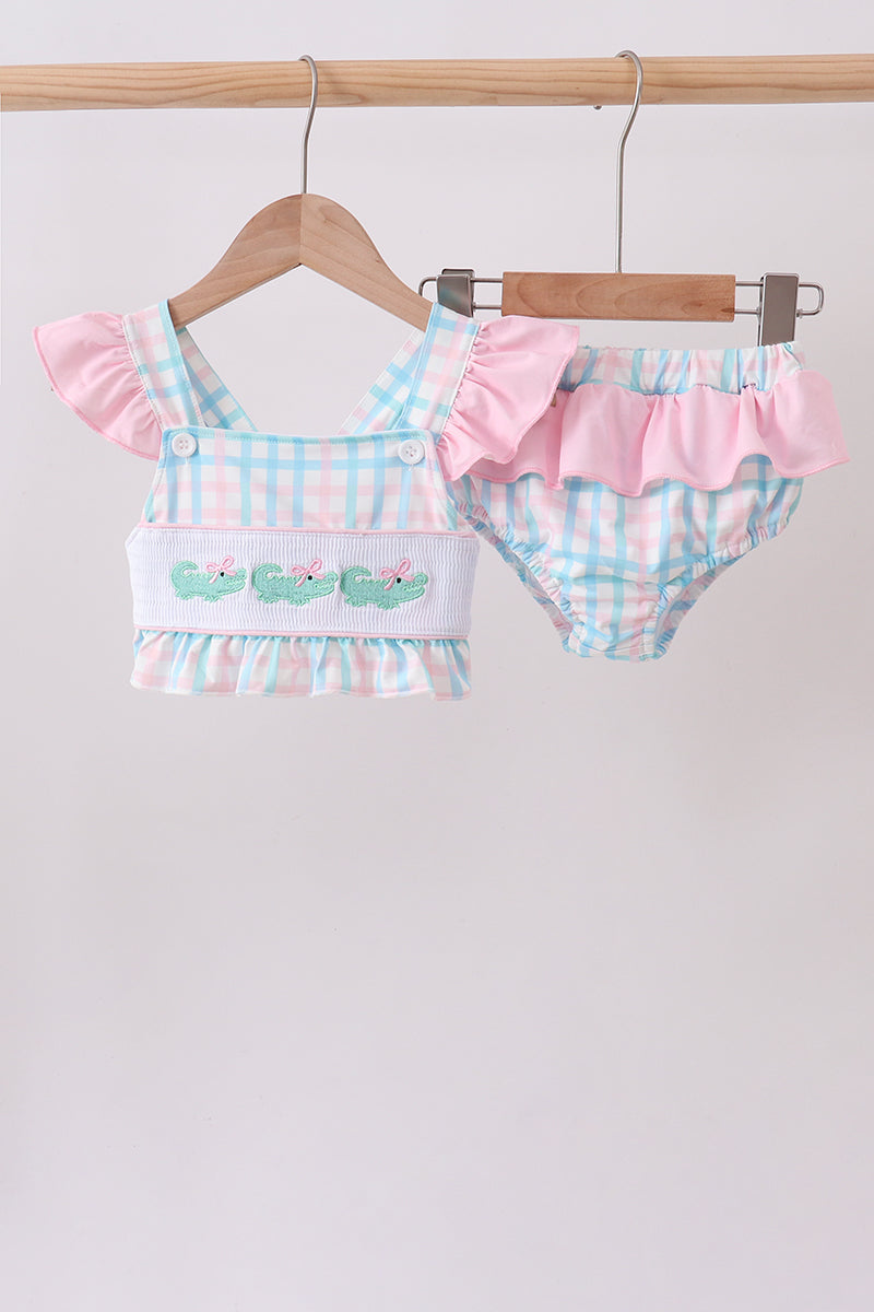 Pink crocodile print on gingham smocked 2-piece swimsuit with pink ruffled accents and matching bottoms.