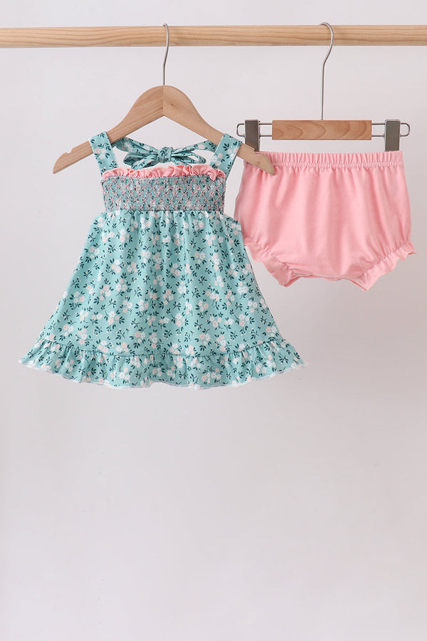 Green floral smocked top with bow straps and ruffled hem, paired with pink bloomers in a two-piece set.