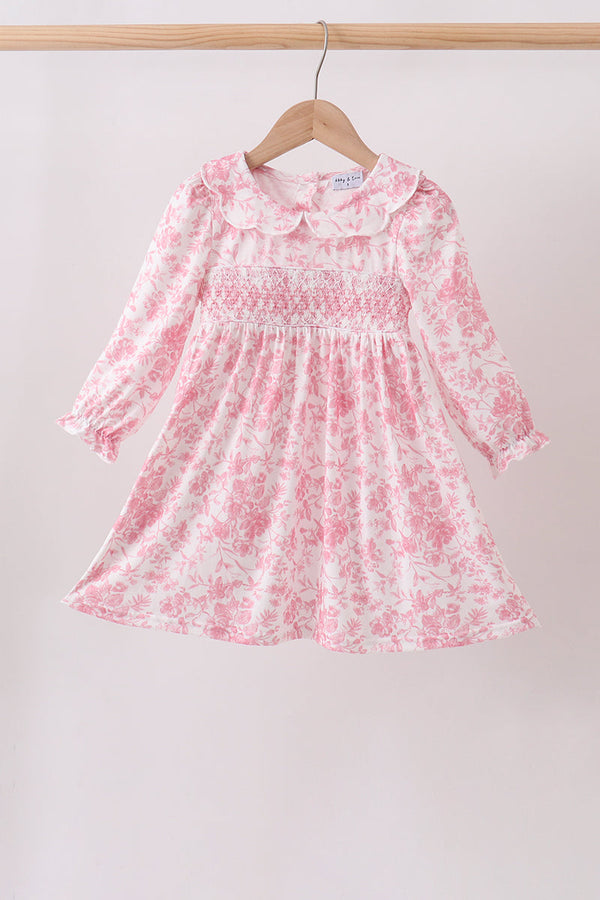 Pink floral smocked dress with long sleeves and a rounded collar, featuring a smocked bodice and flowing skirt.