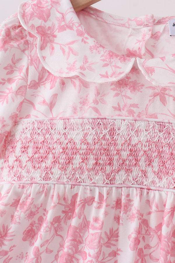 Pink floral smocked dress with a scalloped collar and delicate blooms on light pink fabric.
