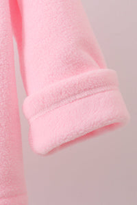 Close-up of a soft pink fleece garment sleeve with a folded cuff, showing the plush texture against a pale pink background.