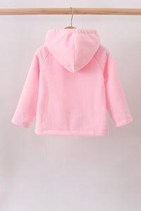 A light pink hooded sweatshirt shown from the back, hanging on a wooden hanger from a light wood clothing rack against a plain off-white wall.