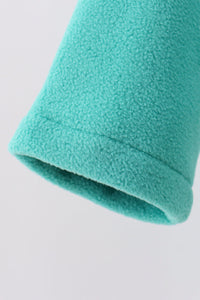 A close-up of a turquoise fleece fabric sleeve or cuff, showing the soft textured material and folded hem against a plain light gray background.