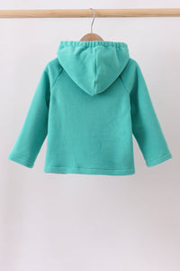 A mint green hooded sweatshirt hanging on a wooden hanger from a light wood clothing rack, shown from the back against a plain off-white background.