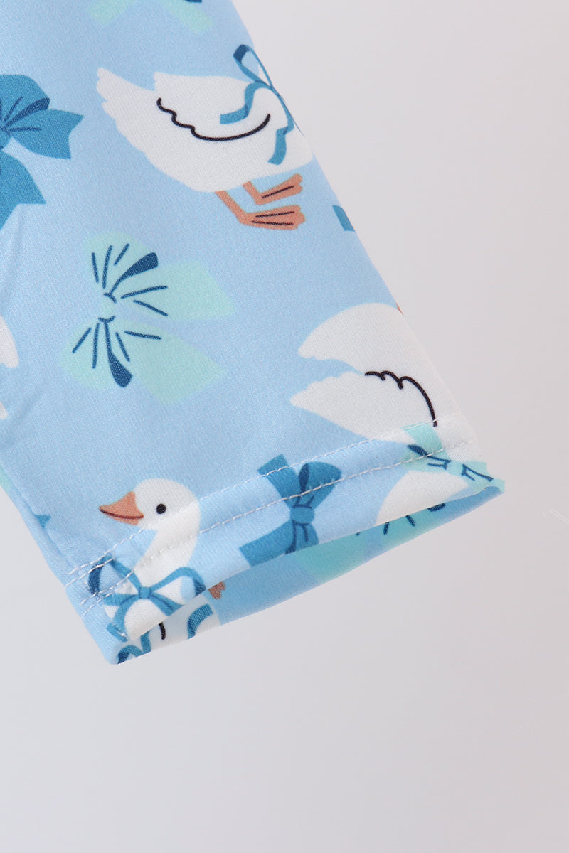 Light blue dress fabric featuring white goose prints with blue bows and playful ruffle details for a whimsical, elegant look.