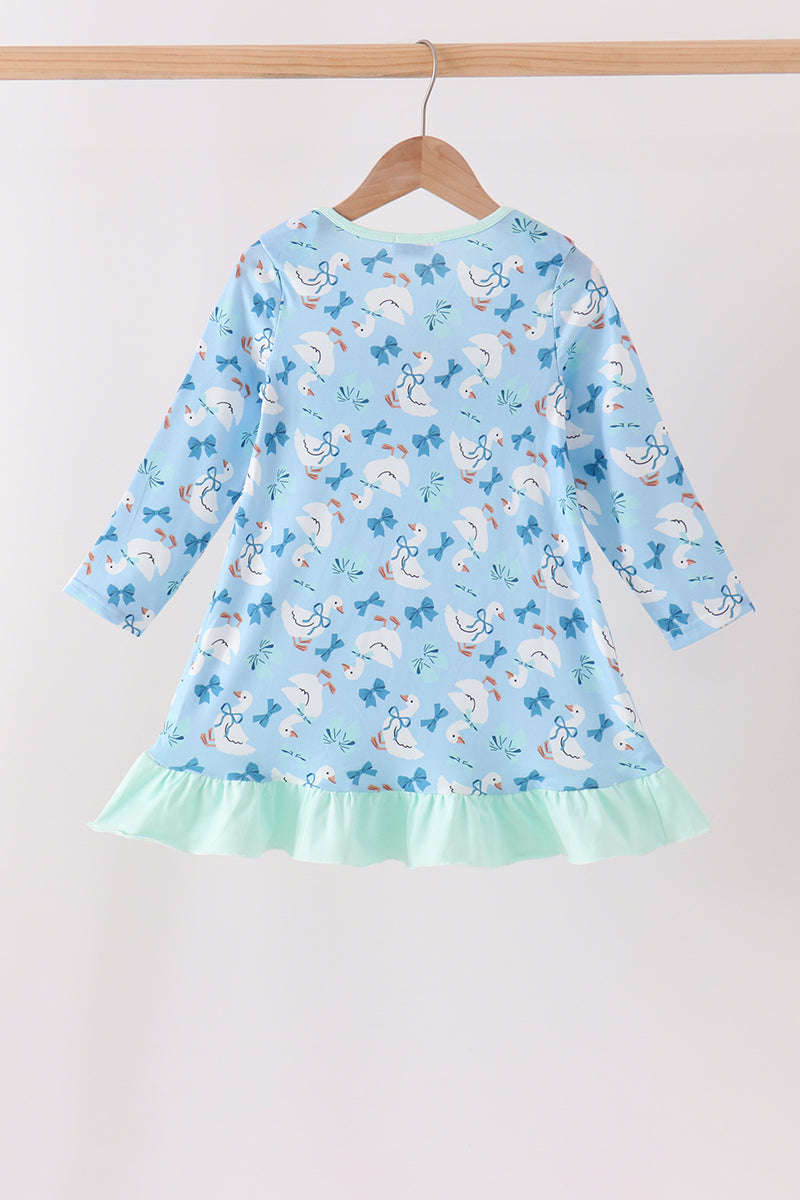 Back view of blue goose print dress with bow pattern and mint green ruffle hem hanging on a wooden hanger.