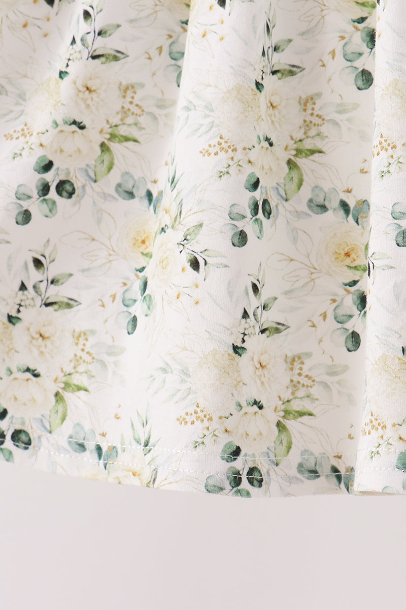 Sage floral print fabric detail with green eucalyptus leaves and cream blossoms, featuring delicate hem stitching on ruffle pants.
