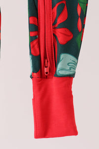 Close-up of a sleeve or garment cuff with a red zipper, red solid cuff, and a dark green floral print with red and light blue flowers.