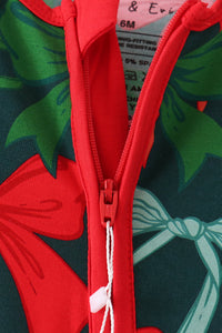 Close-up of a children's zip-up garment with a red zipper and trim, featuring a festive holiday print with red bows and green leaves on a dark background.