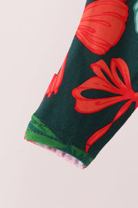 Close-up of a sleeve or cuff featuring a dark green base with large red floral motifs and a green striped inner lining, shown against a plain light background.