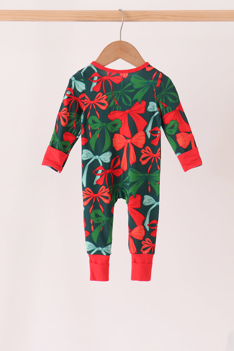 A baby long-sleeve one-piece jumpsuit with a festive Christmas print of red bows, green leaves, and light blue snow globes on a dark green background. It is shown hanging on a wooden hanger against a plain off-white background.