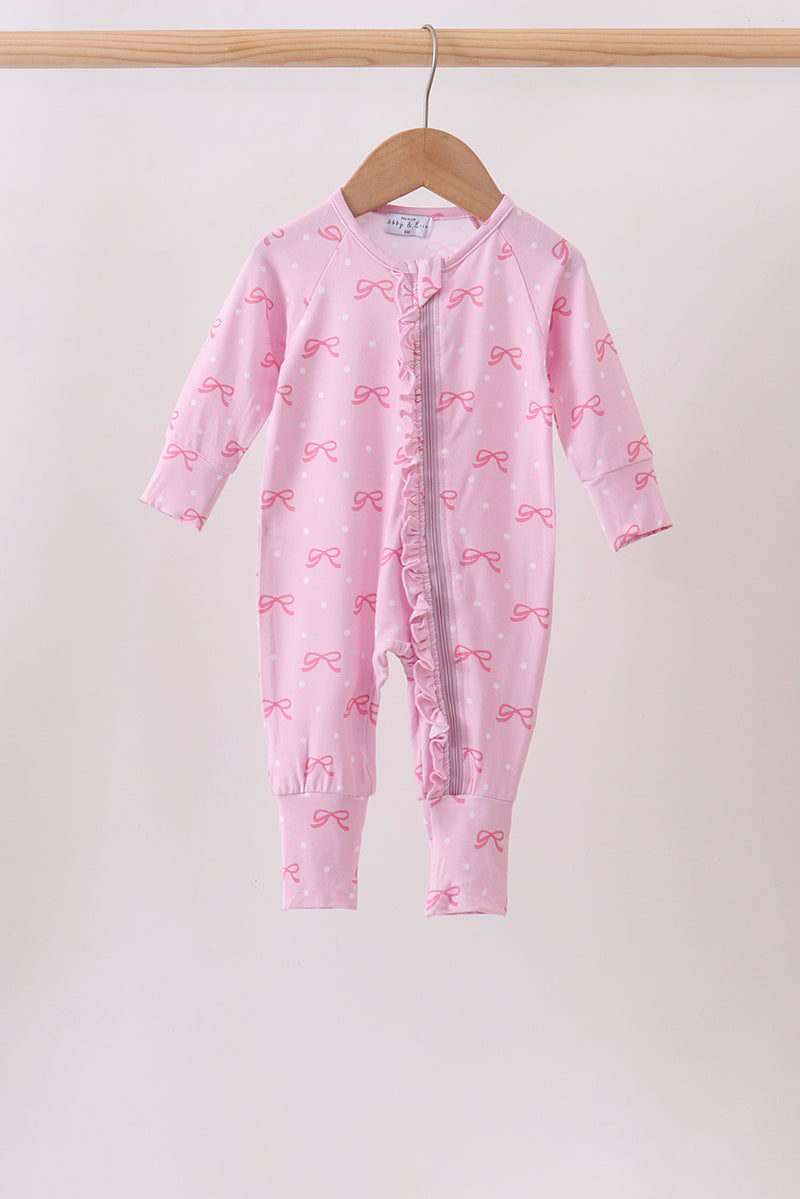 Pink bow print baby romper with ruffled zipper, hanging on wooden hanger. Soft pink one-piece with playful bow pattern for infants.