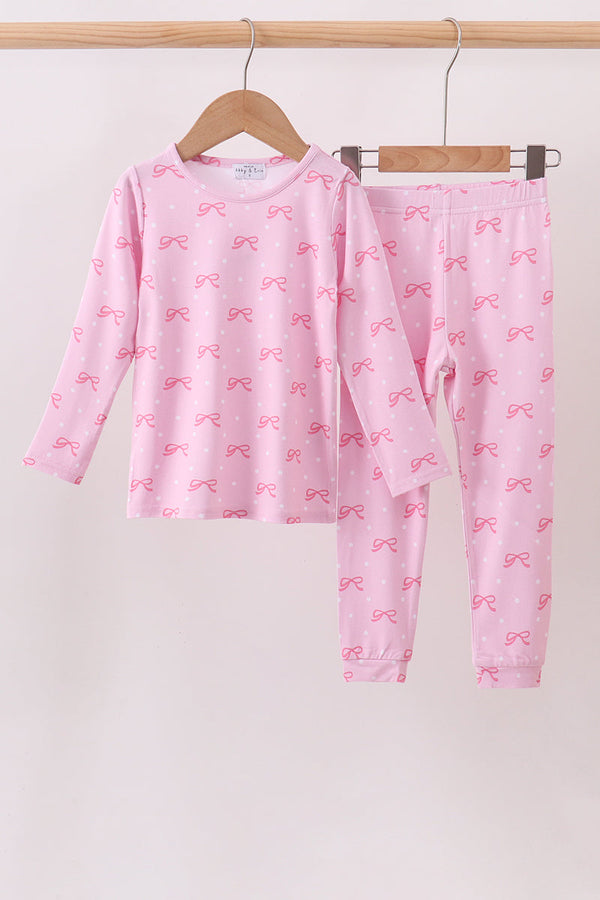 Pink bow print long sleeve top and pants set for kids hanging on a wooden hanger. Soft, comfortable mix-and-match outfit.