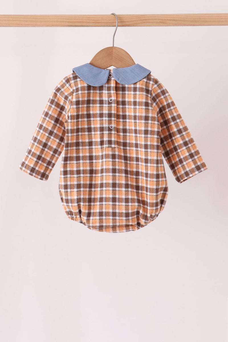 A baby long-sleeve plaid romper hanging on a wooden hanger. The romper features a warm orange and brown plaid pattern with a contrasting light blue Peter Pan collar.