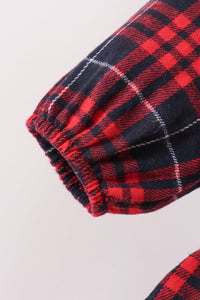 Close-up of a red and black plaid fabric sleeve with an elasticized cuff, shown against a light neutral background.