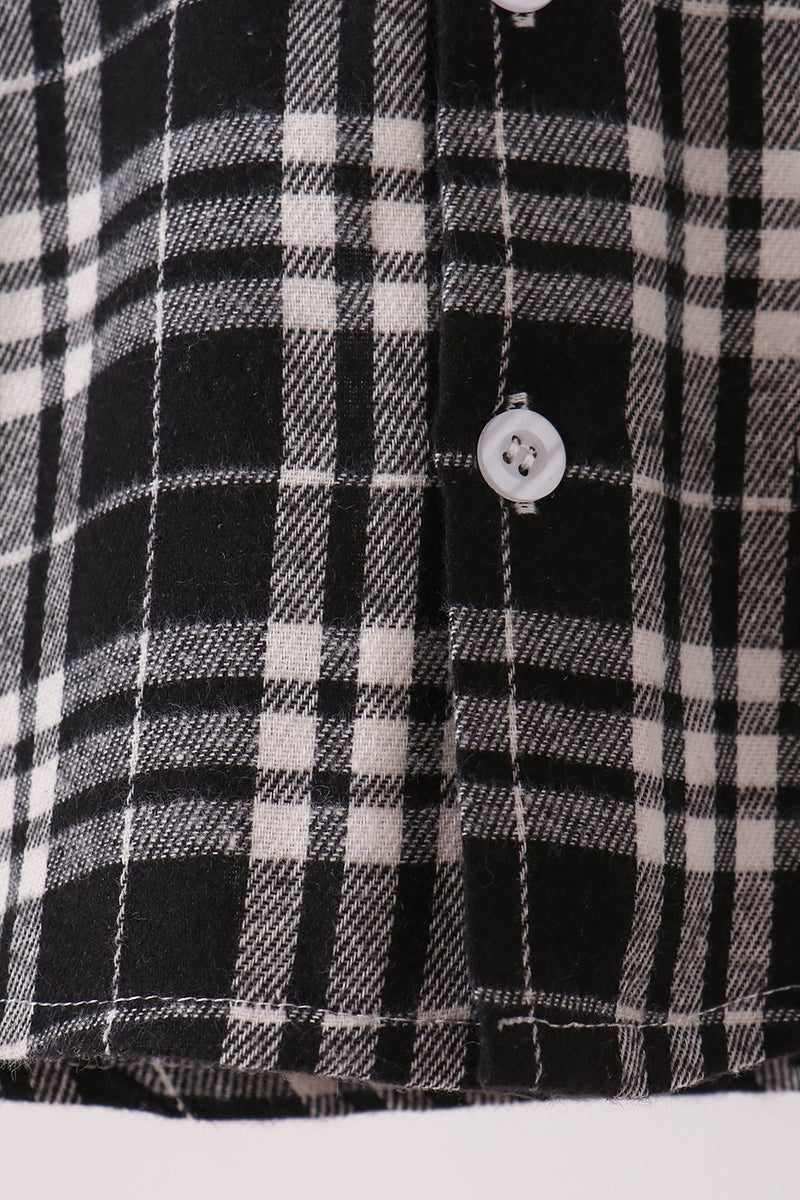 Close-up of a black and white plaid button-down shirt fabric, showing the weave pattern and a white button.