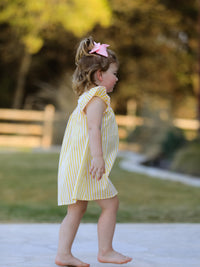 Spring/Summer Chick Floral Embroidery Smocking Girls Dress worn by a girl with a pink bow outdoors