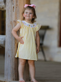 Little girl in a yellow-striped smocked dress with chick floral embroidery and pink bow