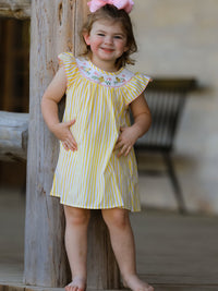 Spring/Summer chick floral embroidery smocking girls dress on a smiling toddler in a yellow striped dress