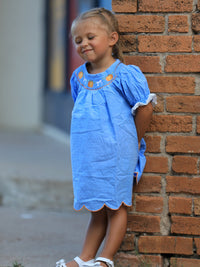 Blue baby girl dress with pumpkin embroidery, lace smock and scalloped orange hem for Thanksgiving and Halloween.