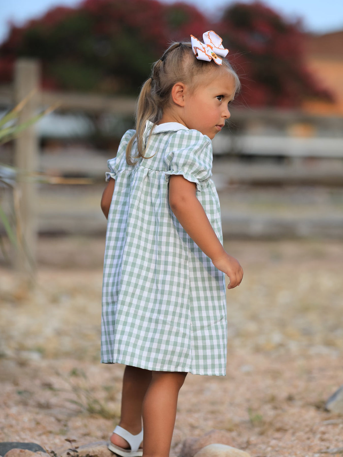 Little girl in a green plaid dress with a pumpkin applique, perfect for fall, Halloween and Thanksgiving.