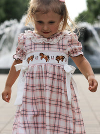 Pink plaid girls dress with horse embroidery, smocked bodice, ruffled collar, and white side bows.