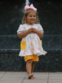 Girl in back-to-school pastel dress with pencil bow pockets, ruffle hem, and pink bow headband.