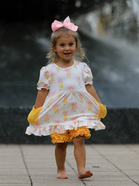 Girl wearing Girls Back To School Pencil Bow Pocket Ruffle Top Shorts Set with pink bow headband outdoors.