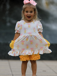 Girl in back-to-school white top with pink bows and yellow ruffled shorts, pink hair bow.