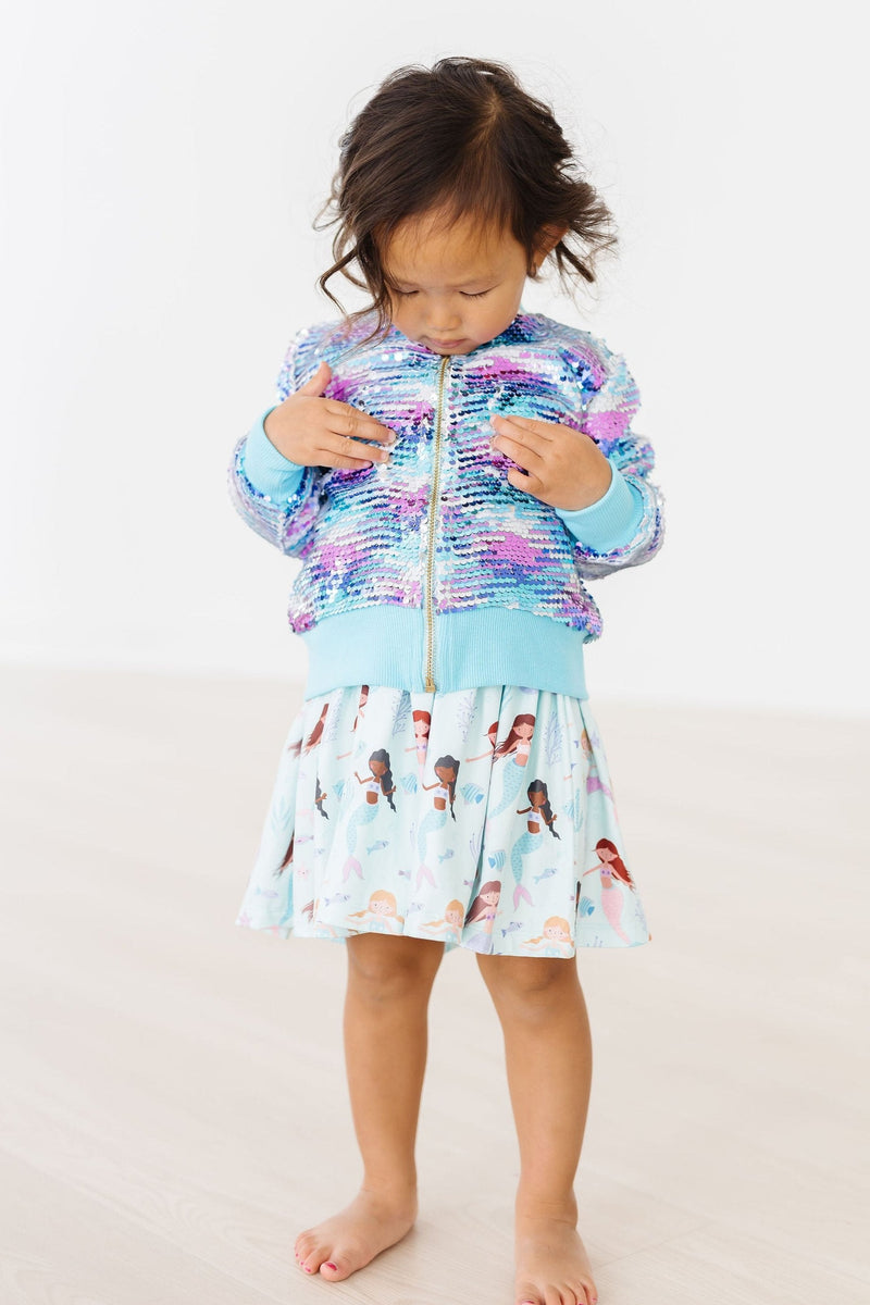 Young girl playfully showcasing the Mermaid Sequin Jacket with a matching skirt, perfect for imaginative adventures.