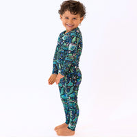 Child wearing The Second-Skin 2-Piece Long Sleeve Pajama, Mystic Mama Blue, colorful print, smiling.