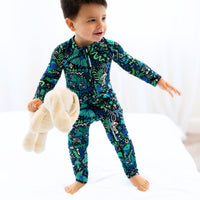 Child wearing The Second-Skin Convertible Romper in blue with a zippered front and bold print.