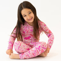 Young girl in pink The Second-Skin 2-Piece Long Sleeve Pajama by Mystic Mama, smiling.